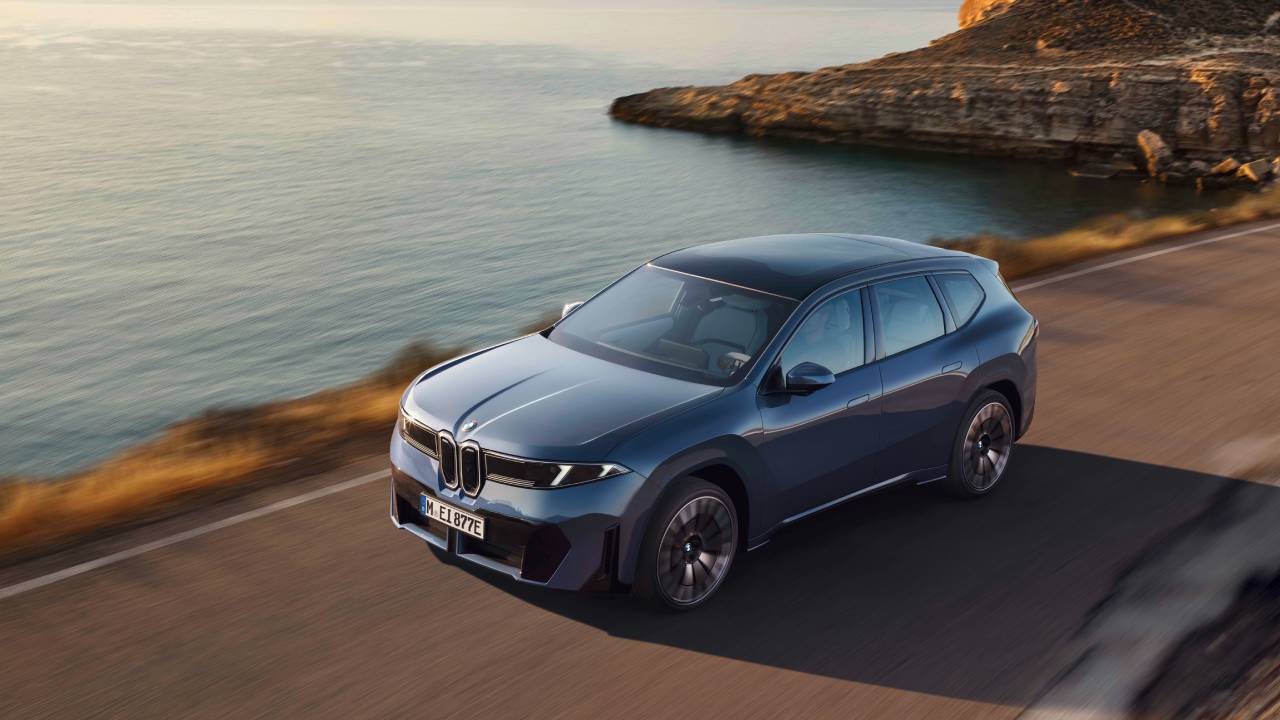 Grå BMW iX3 sedd snett framifrån i solnedgång